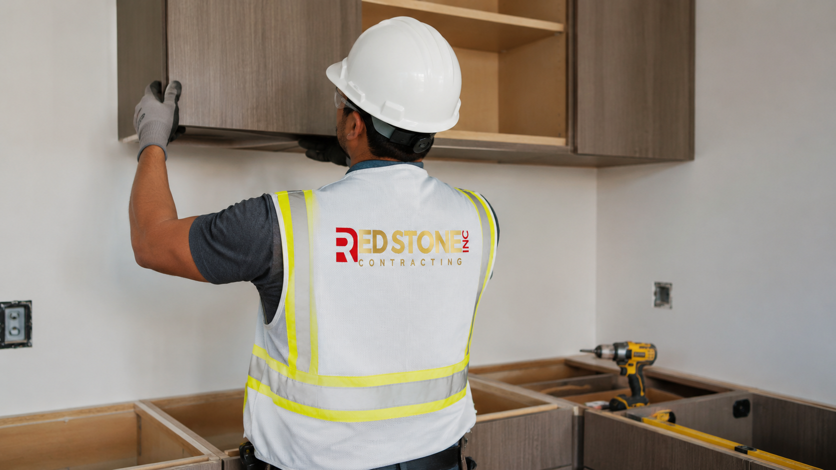 Tradesperson in safety gear fitting base cabinets during a kitchen renovation Scarborough project