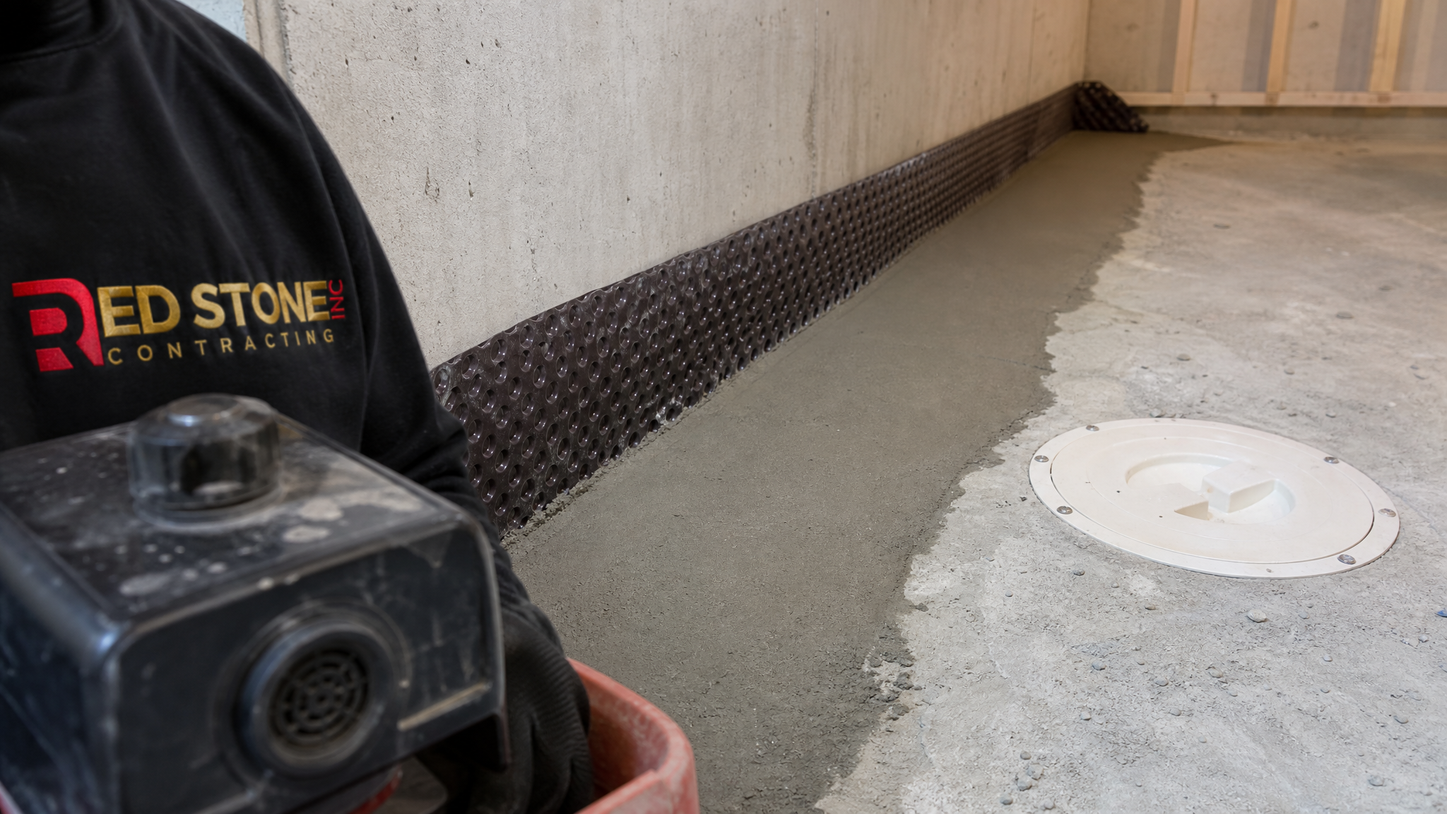 Close-up of an interior perimeter drainage channel and sump pit installed during basement waterproofing