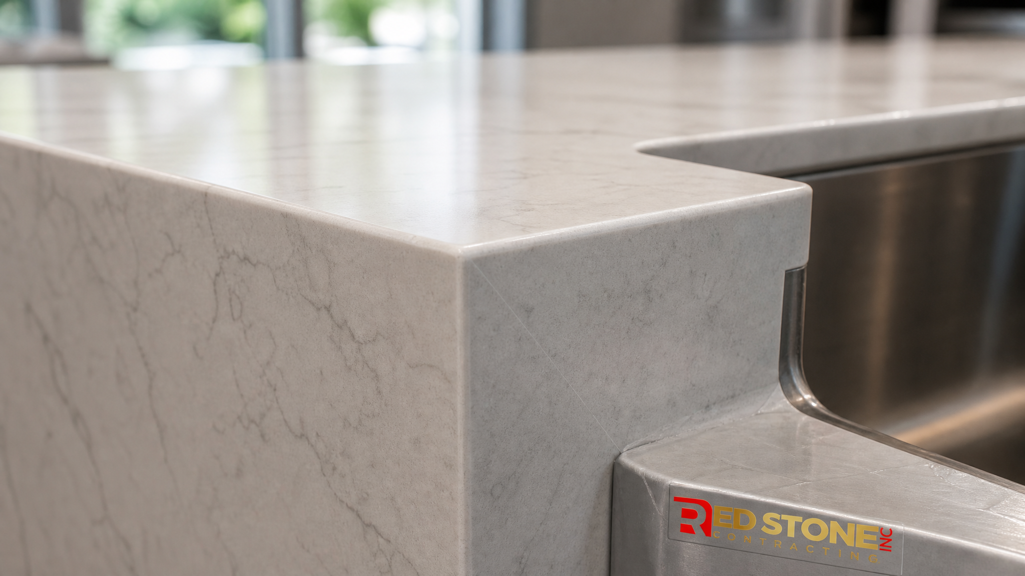 Close-up detail of a mitred waterfall edge and undermount sink cutout on an engineered countertop