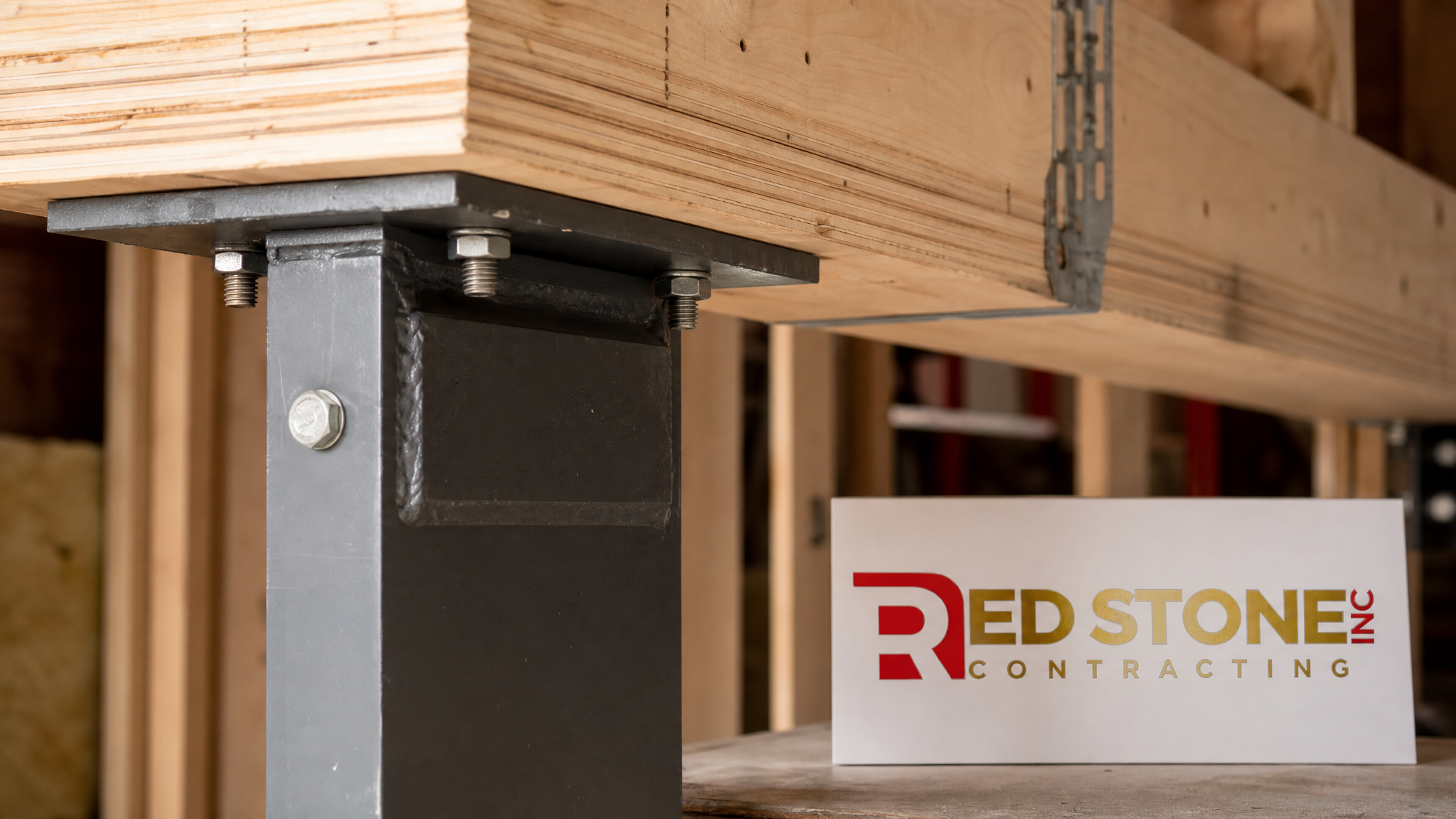 Close-up of a steel post and bearing plate carrying a new beam after load-bearing wall removal