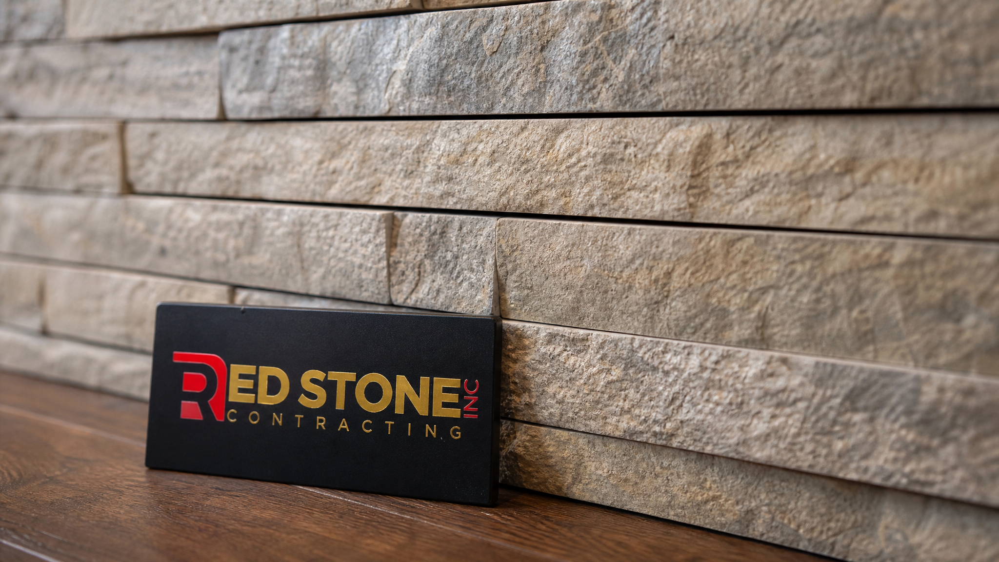 Close-up detail of stone veneer feature wall Toronto installation showing tight dry-stack joints, warm stone tones, and Red Stone Contracting sign placard